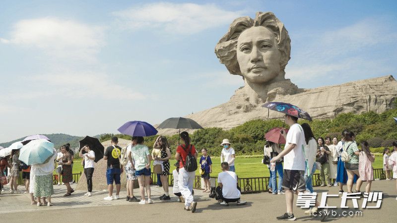 游客纷纷在毛泽东青年雕像前合影留念。