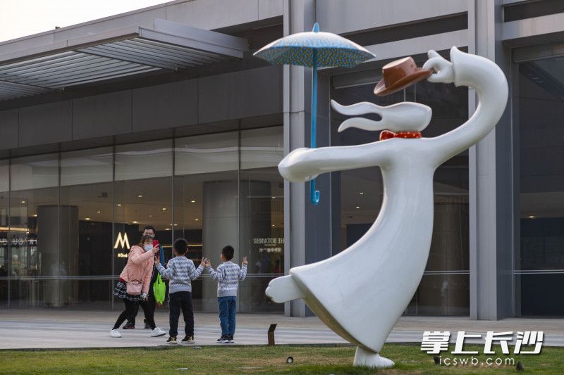 在长沙国金中心，由韩国艺术家金大成创作的雕塑《万花嬉春》吸引了不少市民游客与其合影。