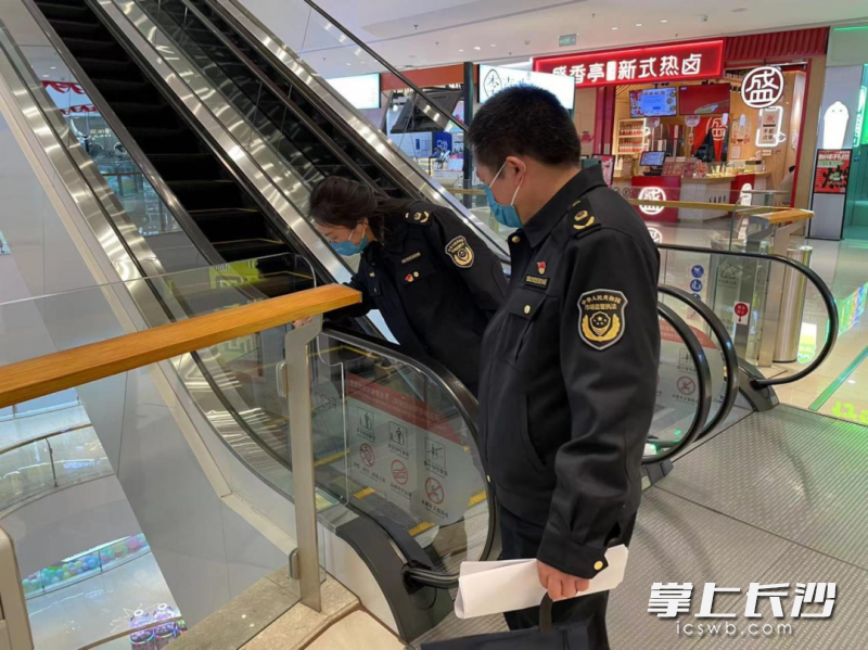 执法人员正在对商场内电梯进行安全检查。