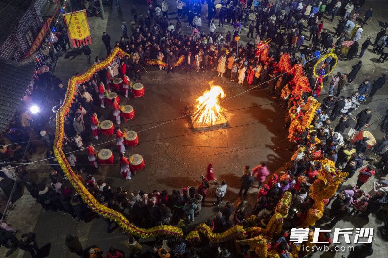 除夕夜，湘阴县文星街道三峰社区举行迎春社火表演活动，数百人围着篝火敲锣打鼓、舞狮拱虾，一起过大年。均为长沙晚报全媒体记者 郭雨滴 摄