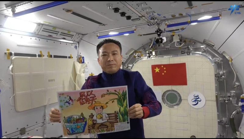 航天员在“天宫”展示杨雨橙的画作“禾下乘凉梦”。视频截图